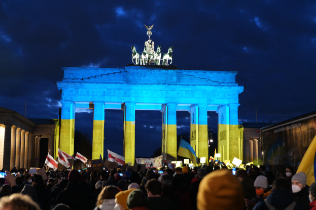 Eine Menschenmenge steht vor dem Reichstagsgebäude in Berlin, Deutschland, mit Fahnen und Plakaten in den Händen, mit einer Banner auf der rechten Seite.