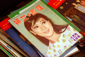 Eine Sammlung von Zeitschriften auf einem Tisch, wobei die erste ein Bild einer Frau zeigt.