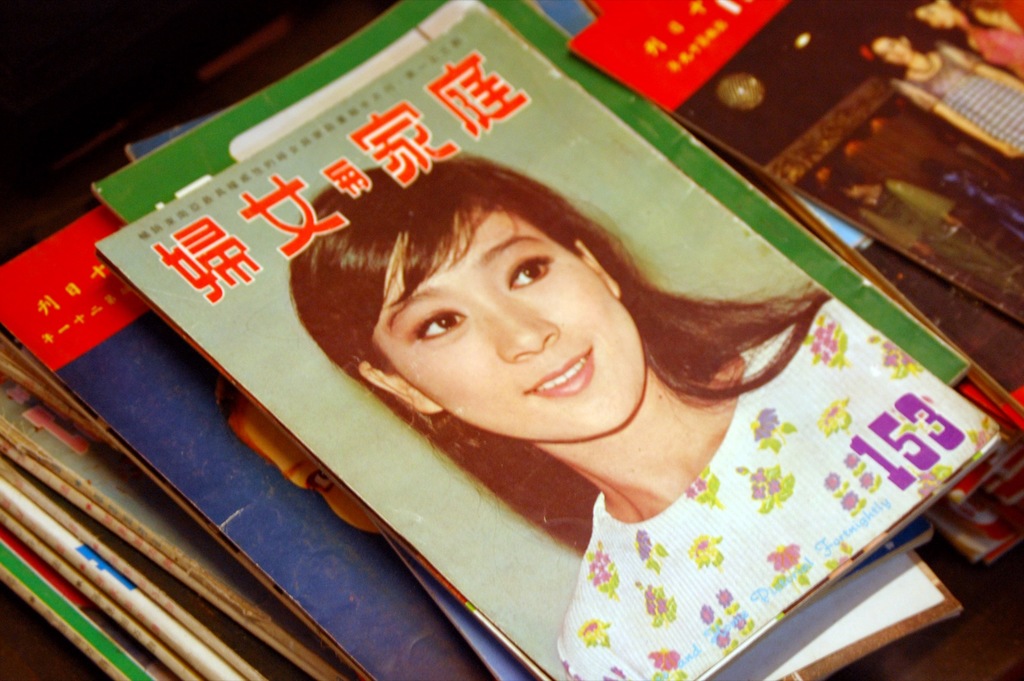 Eine Sammlung von Zeitschriften auf einem Tisch, wobei die erste ein Bild einer Frau zeigt.