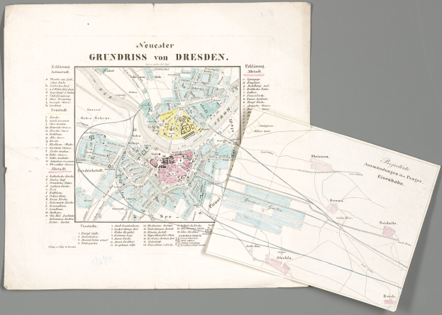 Ein detaillierter alter Stadtplan von Dresden, Deutschland, mit zwei Papieren im Vordergrund vor einem grauen Hintergrund.