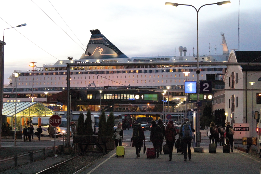 Eine volle Straße mit Menschen, die Taschen tragen und an Polen und Gebäuden vorbeigehen.