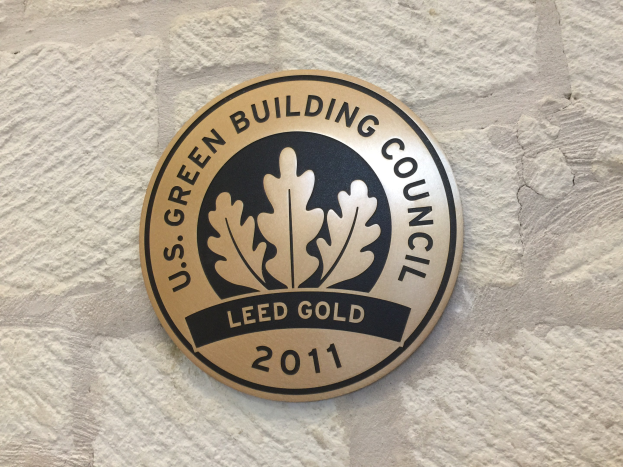 Logo der U.S. Green Building Council an einer Gebäudefassade, mit einem grünen Schild mit weißer Umrandung, fetter schwarzer Schrift und einem umgebenden Lorbeerkranz.