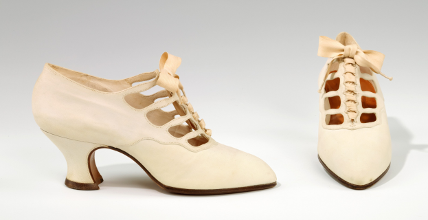 Weiße, spitz zulaufende, niedrige Schuhe mit Schleife auf weißem Hintergrund.