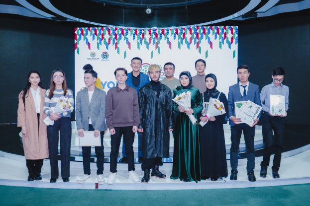 Gruppe von Menschen auf einer Bühne mit Blumensträußen und Urkunden, vor einem Hintergrund mit der Aufschrift "Youth Solar Awards 2019".