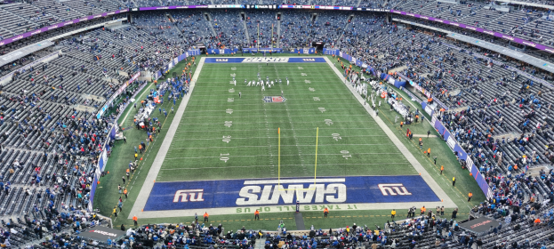 Ein Fußballstadion voller Zuschauer, Spieler, Pfosten und Schilder mit Text, alles sitzend in Stühlen, schafft eine lebendige Atmosphäre.