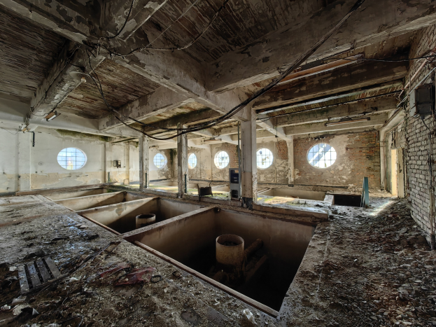 Verlassenes Gebäude im Inneren des Chernobyl-Ausschlussgebiets mit verstreuten Trümmern, freiliegenden Wänden, Decke und strukturellen Elementen.