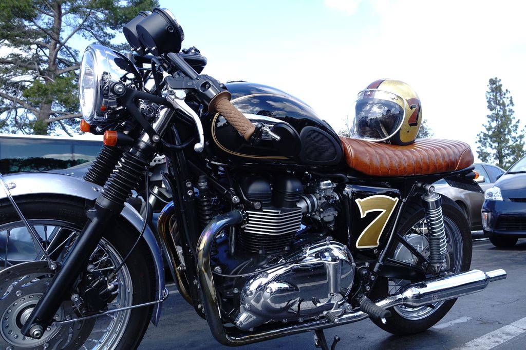 Ein Fahrrad mit Helm befindet sich in der Mitte des Bildes, umgeben von Autos, Bäumen, Himmel und einer Straße unten.