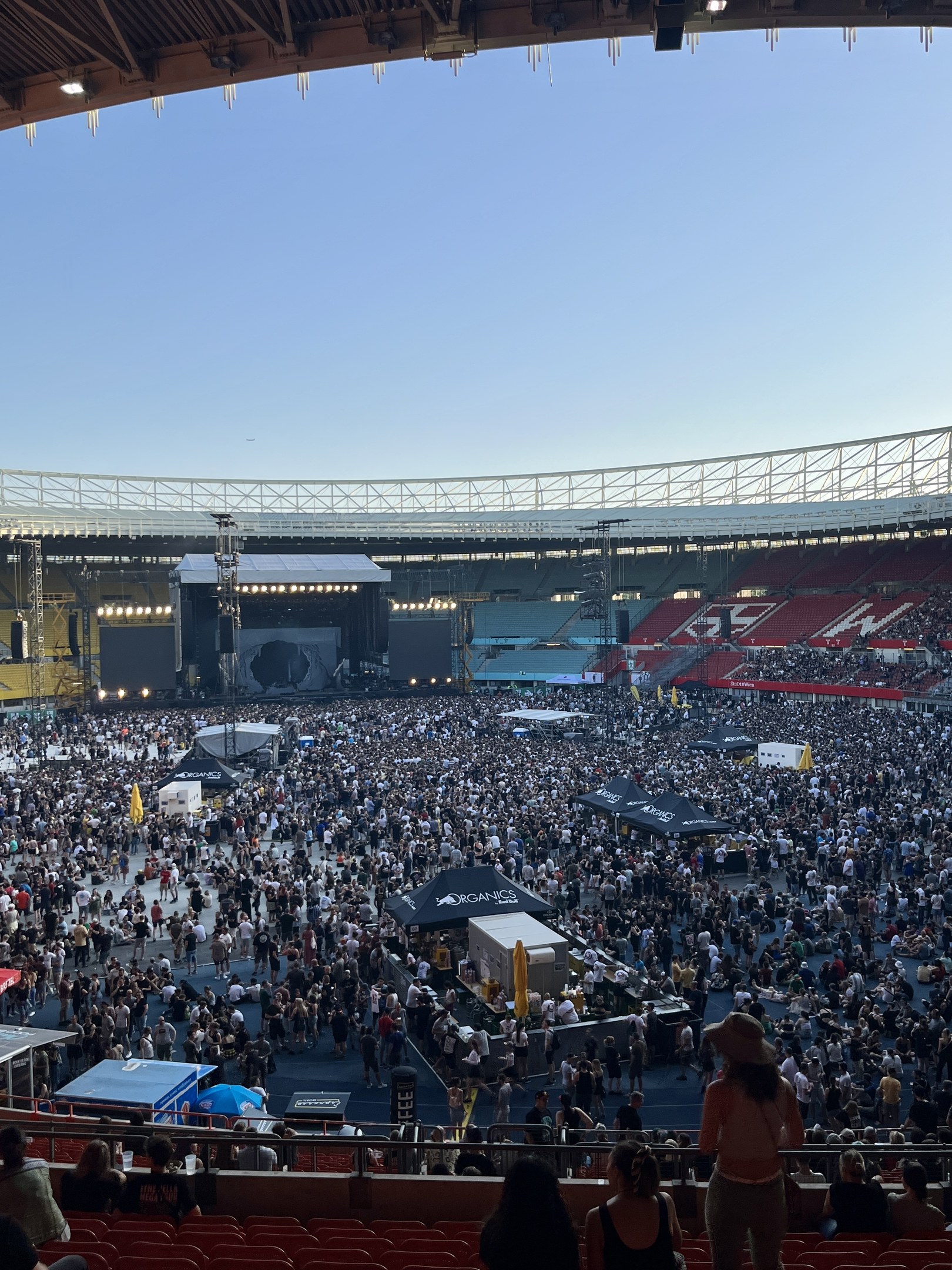 Große Menschenmenge auf Tribünen und Stehplätzen in einem Stadion mit Zelten und Beleuchtung unter einem überdachten Bereich im O2 Arena in London.