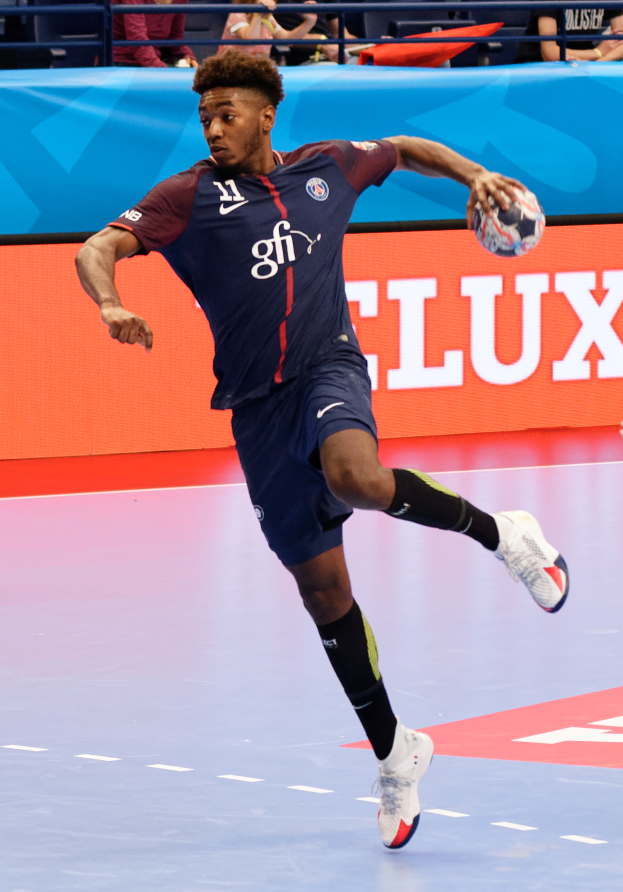 Ein Mann in einer blauen Uniform, der als Paris Saint-Germain identifiziert wird, spielt Handball in einer Halle während der Futsal-Weltmeisterschaft 2019, mit Zuschauern im Hintergrund.