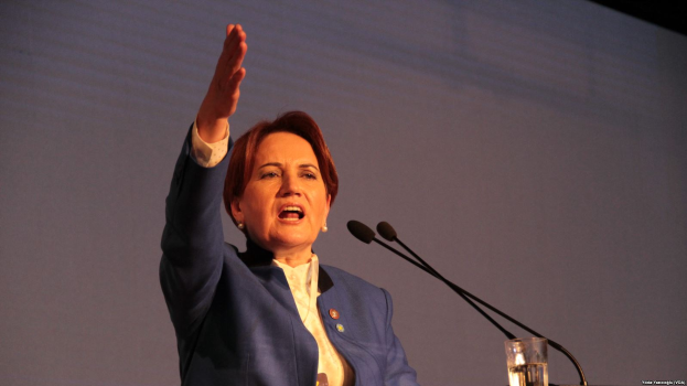 Eine Frau steht an einem Podium mit zwei Mikrofonen und einem Glas Wasser und hält eine Rede vor einem Bildschirm, wahrscheinlich zu einer Regierungsentscheidung, Frauenrechte zu verbieten.