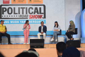 Eine Gruppe von Menschen sitzt auf einer Bühne mit einer Frau in der Mitte, die ein Mikrofon hält, ein Publikum im Vordergrund und ein Banner mit der Aufschrift 'Politischer Straßenkampf 2019' im Hintergrund.