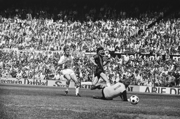 Schwarzes Foto von Männern, die auf einem Feld Füßball spielen, mit Zuschauern im Hintergrund und einer "Bundesliga 1978-79 Ajax 1-1 Hannover 96"-Aufschrift.