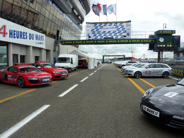 Autos stehen vor einem Gebäude auf der rechten Seite, mit Schildern auf der rechten Seite.