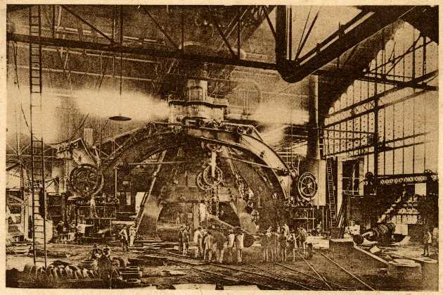 Ein Schwarz-Weiß-Foto einer Fabrikszene bei Cadillac Steel Works, das Arbeiter bei der Bedienung einer großen Maschine zeigt, umgeben von Leitern und Stangen.