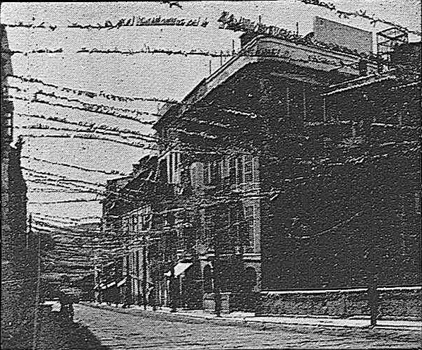 Schwarz-weißes Foto eines Gebäudes mit Stacheldraht oben auf einer Straße mit einem Himmel-Hintergrund, beschriftet mit "New York Post Office, New York City" unten.
