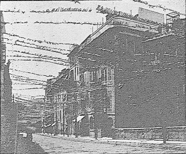 Schwarz-weißes Foto eines Gebäudes mit Stacheldraht oben auf einer Straße mit einem Himmel-Hintergrund, beschriftet mit "New York Post Office, New York City" unten.