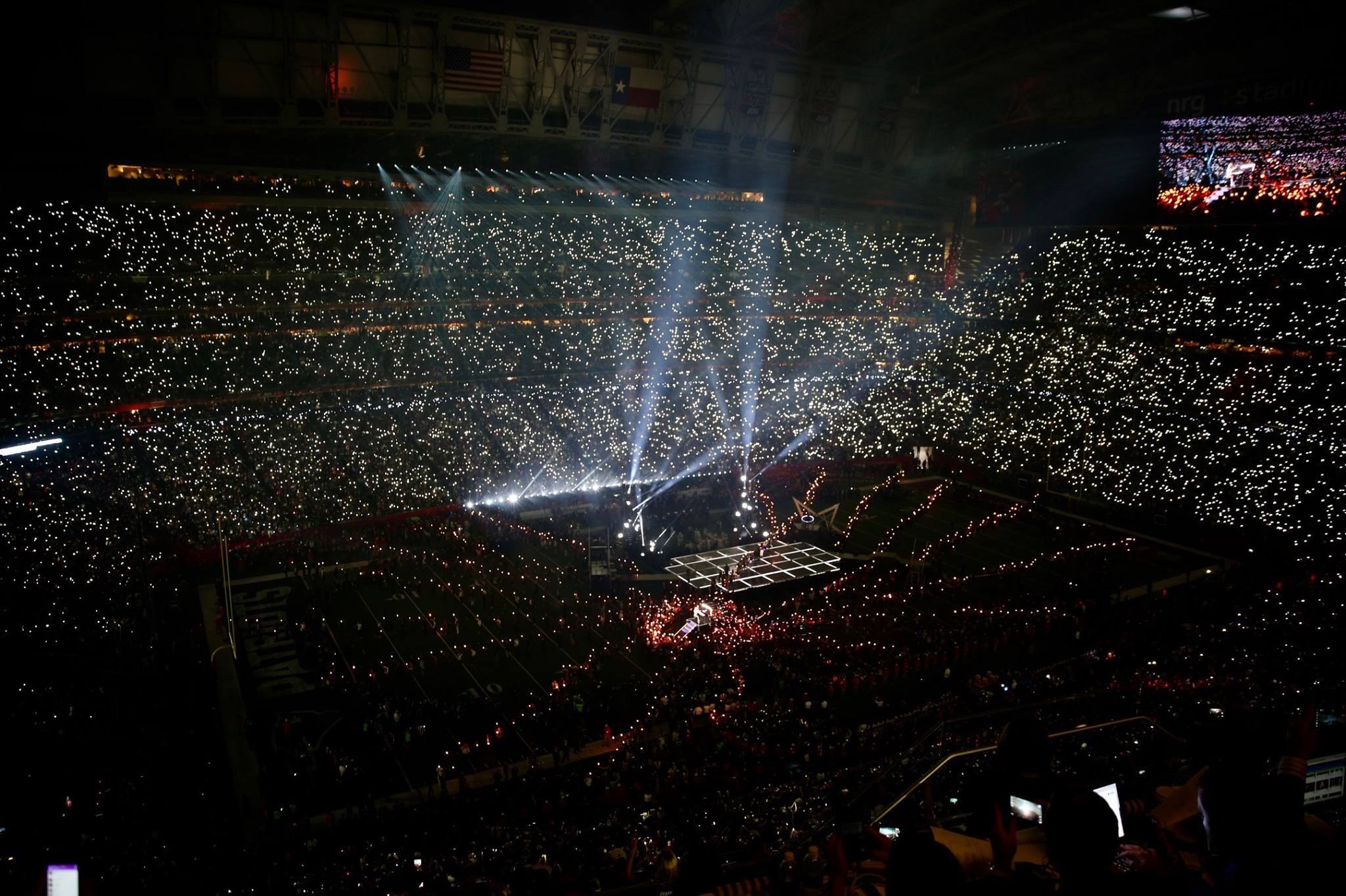 Große Menschenmenge in einem hell erleuchteten Stadion bei Nacht mit einem Bildschirm, der die Ergebnisse der Super Bowl XLVII-Halbzeitshow anzeigt.