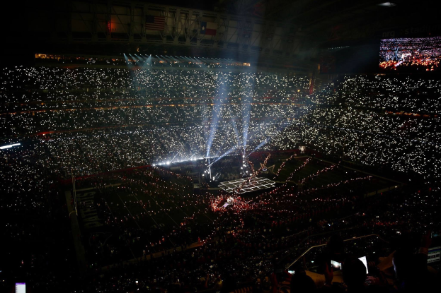 Große Menschenmenge in einem hell erleuchteten Stadion bei Nacht mit einem Bildschirm, der die Ergebnisse der Super Bowl XLVII-Halbzeitshow anzeigt.