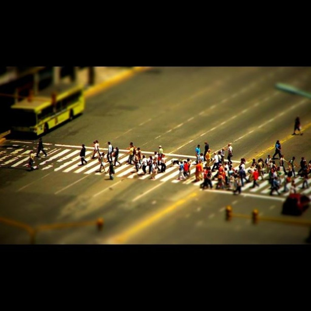 Eine Stra√e mit Menschen, einem Bus, Ampeln und einem Auto auf der rechten Seite.