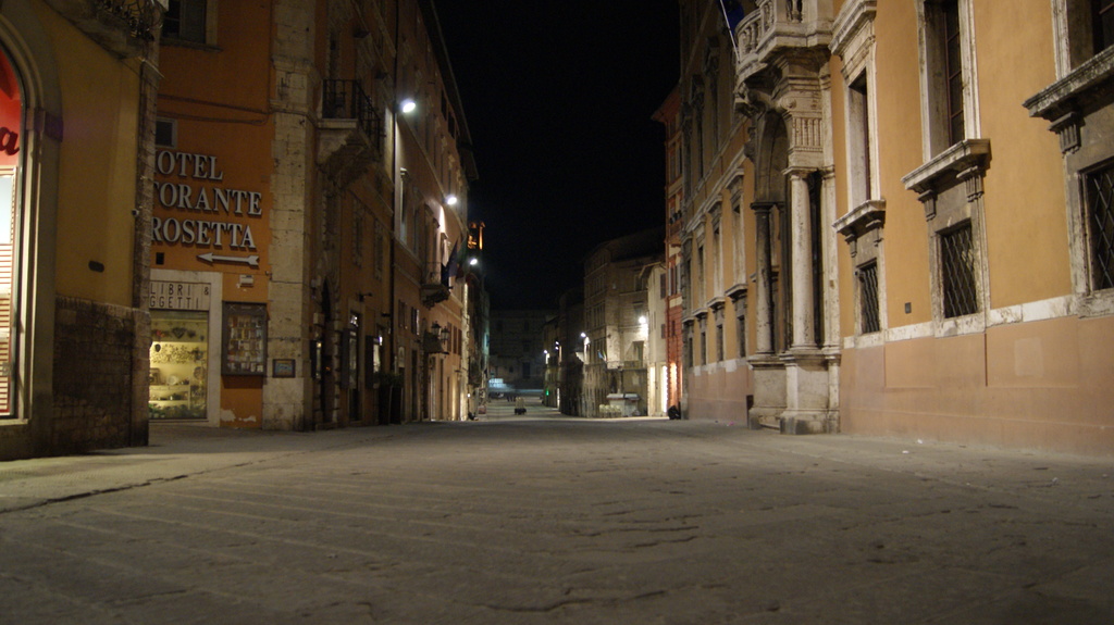 Eine nächtliche Straßenszene mit Gebäuden auf beiden Seiten, einem Geschäft auf der linken Seite und Lichtern in der Mitte.