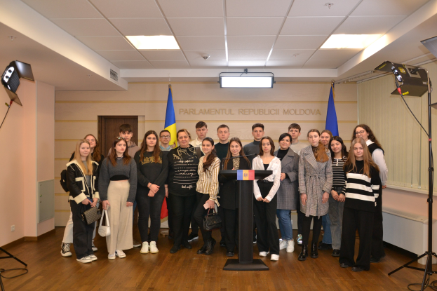 Gruppe von Menschen vor einem Podium mit Mikrofon bei der Moldova Youth Congress 2018, umgeben von Fahnen, einer Wand mit Text, einer Tür, einer Decke und Scheinwerfern.