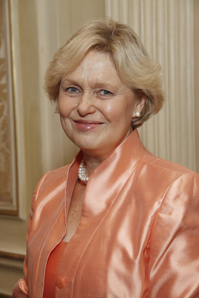 Eine Frau in einem orangen Kleid mit einem Foto Rahmen im Hintergrund.