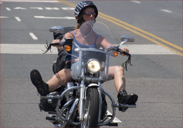 Eine Frau mit einem schwarzen Helm fährt auf der Straße mit einem Fahrrad.