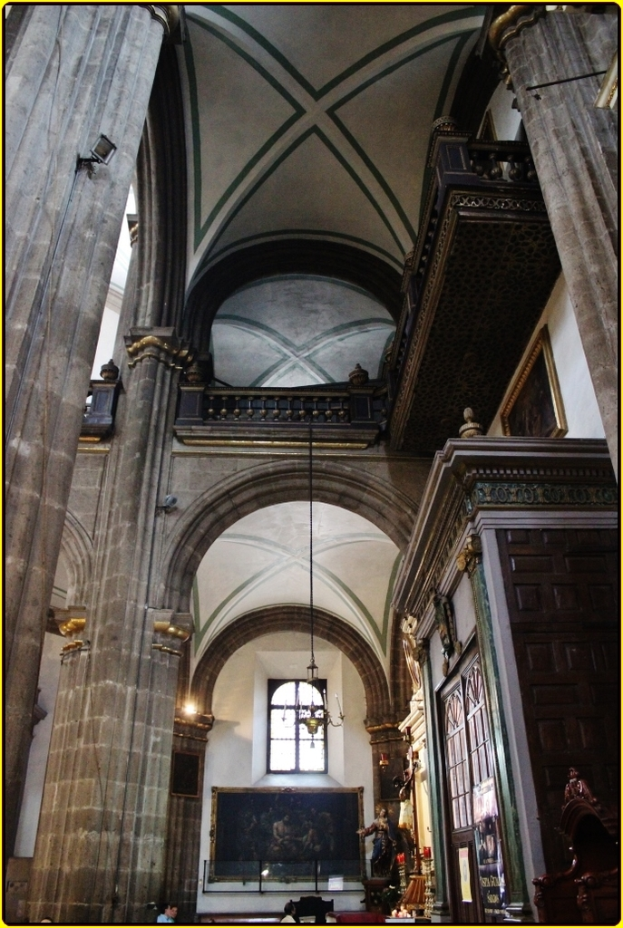 Ein Innenblick eines Palasts mit Schränken, beleuchteten Säulen, Wandskulpturen, einem großen Rahmenbild und einer Deckenleuchte.