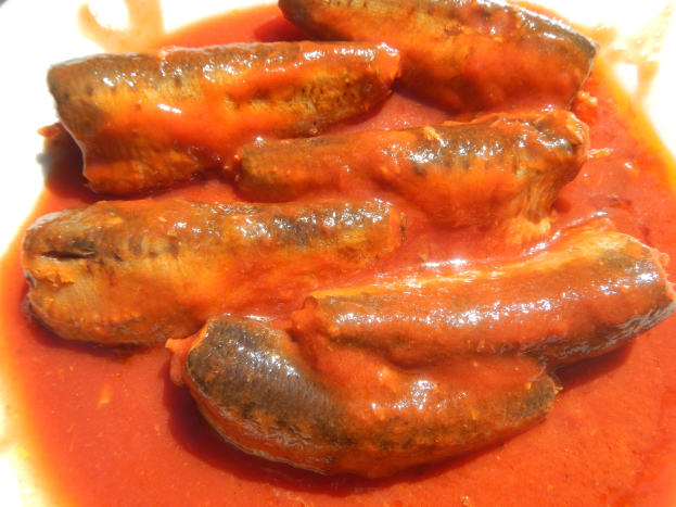 Weißer Teller mit Würsten, die mit roter Sauce bedeckt sind.