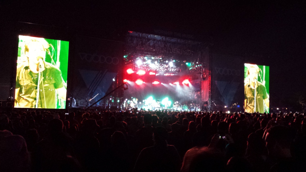 Ein Konzertbild mit einer Menge unten, ein großer Bildschirm links und ein weiterer rechts.