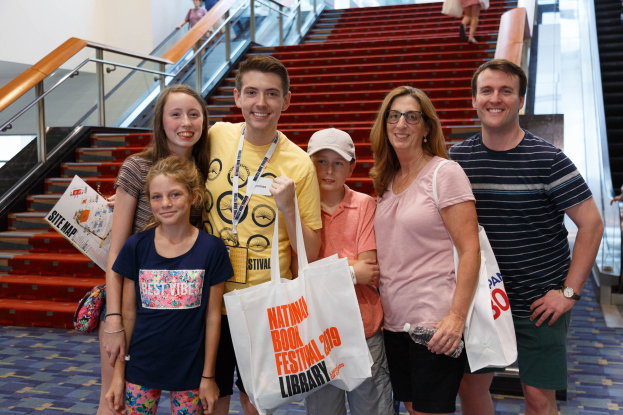 Menschen lächeln und halten Taschen vor einer Rolltreppe auf der Nationalen Buchmesse 2019.
