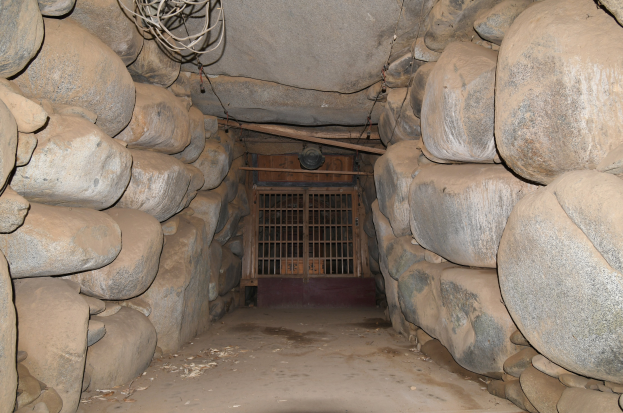 Ein mit Felsen gefüllter Tunnel und ein Metalltor in der Mitte, mit Drähten an der Spitze, die an einen Stolleneingang erinnern.