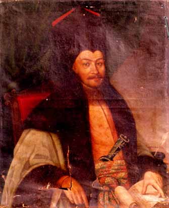 Ein Mann in einem langen Gewand sitzt in einem Stuhl und hält ein Buch und einen Stift in der Hand, mit einem ernsten und nachdenklichen Gesichtsausdruck, der in die Ferne schaut.