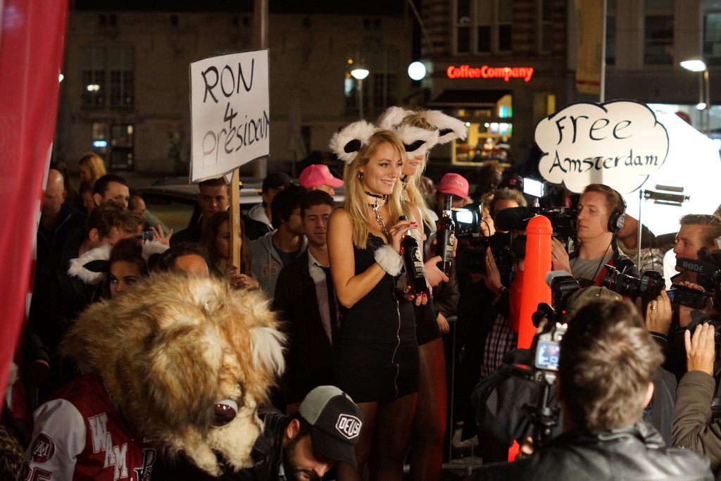 Eine große Menge von Karteninhabern vor Gebäuden und Lichtern, viele fotografieren.