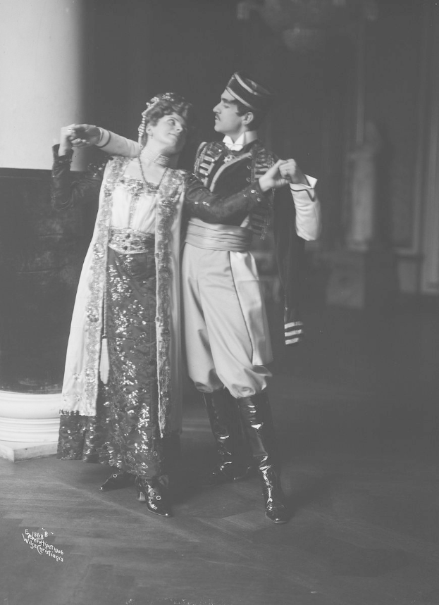 Schwarzes und weißes Foto eines Mannes und einer Frau, die in einem Ballsaal tanzen, mit einer Säule und einer Wand im Hintergrund; der Mann trägt Schuhe.