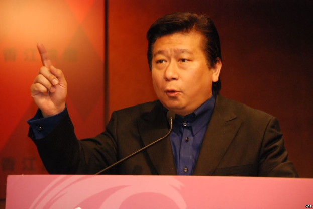 Ein Mann im Anzug und mit Krawatte hält eine Rede an einem Rednerpult mit einem Mikrofon und sieht ernst aus.