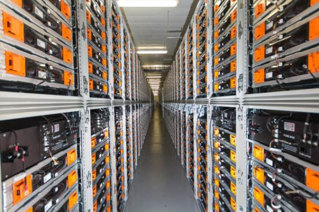 Eine lange Reihe von Servern in einem Rechenzentrum, mit elektronischen Geräten in den Racks und Lampen oben.